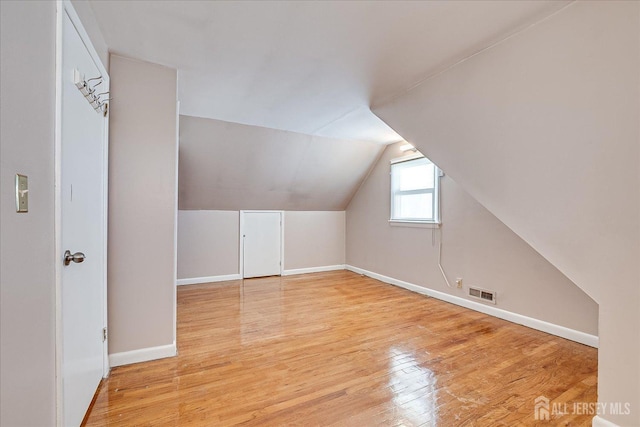 bonus room with lofted ceiling and light wood-type flooring