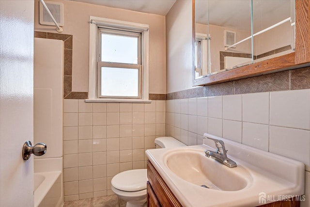 full bathroom featuring vanity, toilet, tile walls, and shower / bath combination