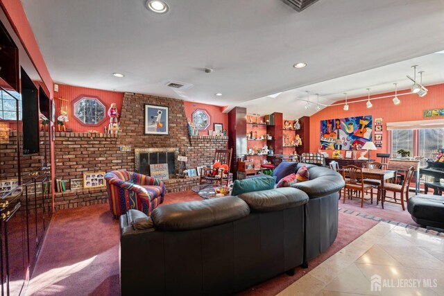 living room with vaulted ceiling, a brick fireplace, and tile patterned floors