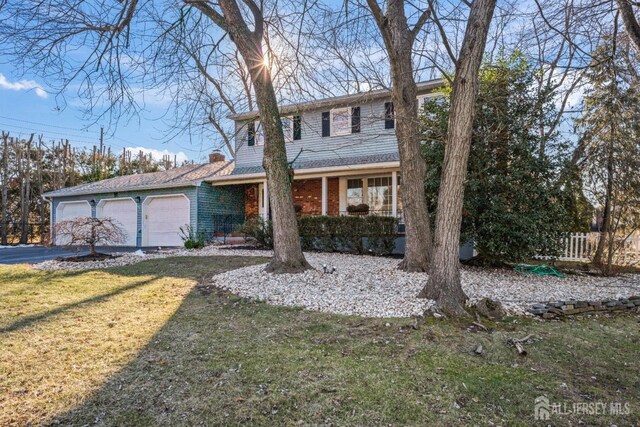 view of front of house with a garage, a front lawn, and covered porch