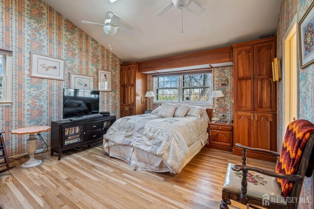 bedroom with ceiling fan, light hardwood / wood-style floors, and vaulted ceiling