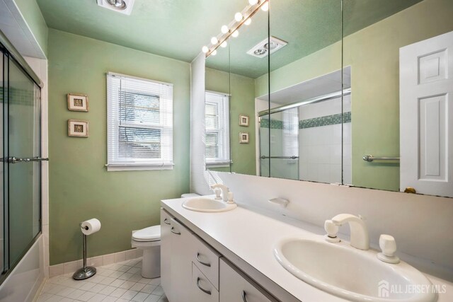 full bathroom featuring bath / shower combo with glass door, toilet, vanity, and tile patterned flooring