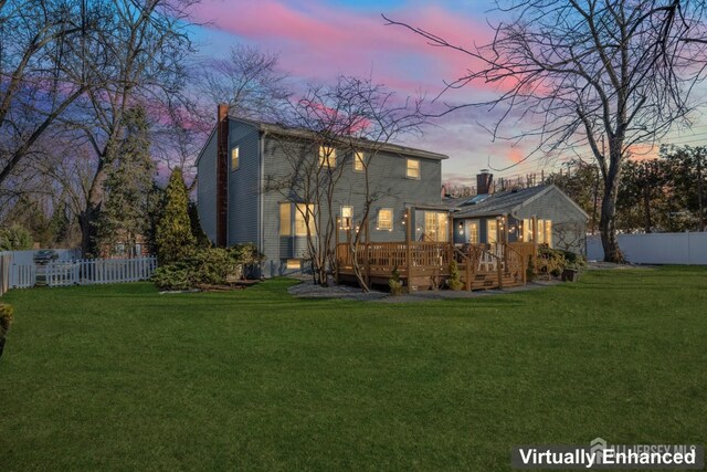 back house at dusk with a wooden deck and a yard