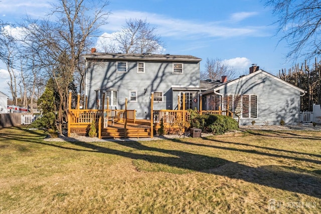 rear view of house featuring a wooden deck and a yard