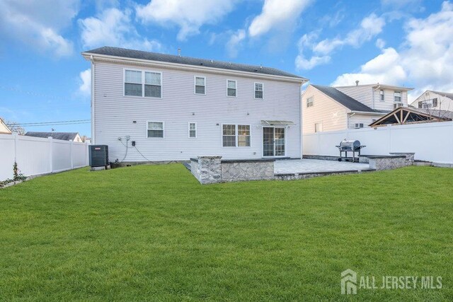 rear view of house with cooling unit, a patio area, and a lawn