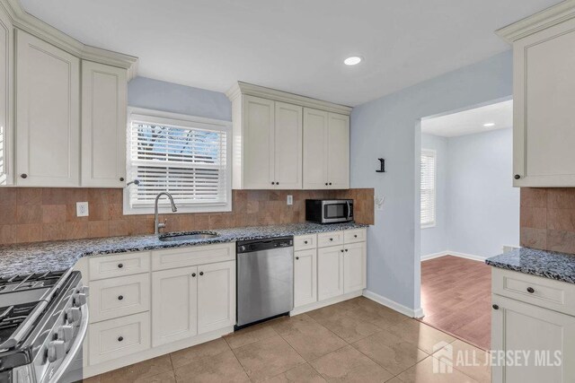 kitchen featuring tasteful backsplash, light stone countertops, sink, and stainless steel appliances