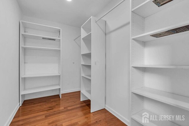 walk in closet with hardwood / wood-style floors