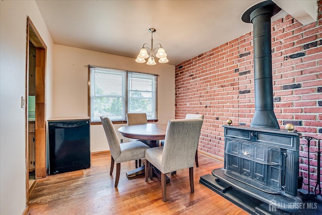 108 Smith St, South Plainfield, NJ 07080 - dining area with a wood stove, light wood-style flooring, a chandelier, and brick wall