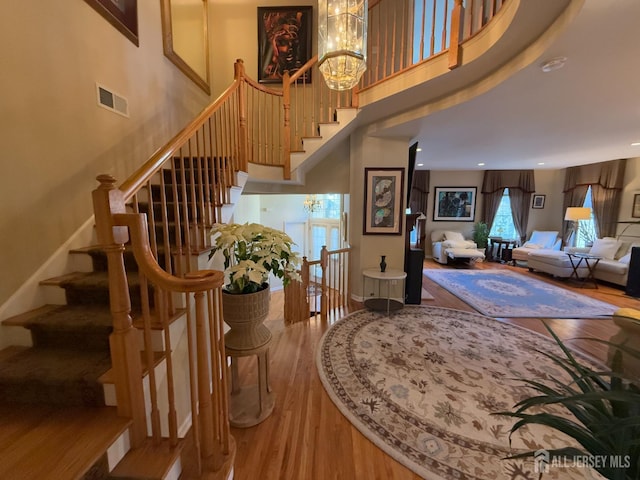 stairway featuring an inviting chandelier, hardwood / wood-style floors, and a high ceiling