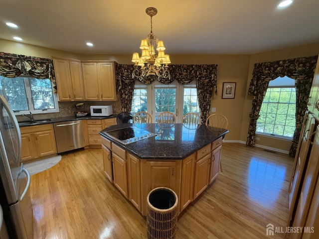 kitchen featuring an inviting chandelier, hanging light fixtures, light hardwood / wood-style flooring, appliances with stainless steel finishes, and a kitchen island