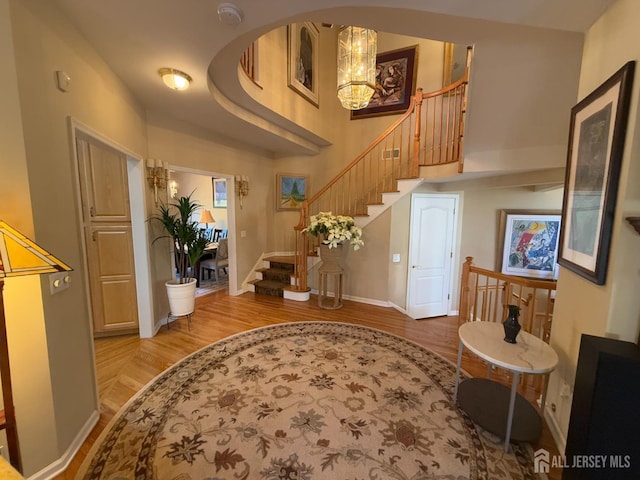 entrance foyer featuring a high ceiling, light hardwood / wood-style flooring, and a notable chandelier