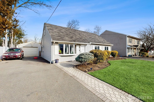 view of front of home with a garage, an outdoor structure, and a front yard