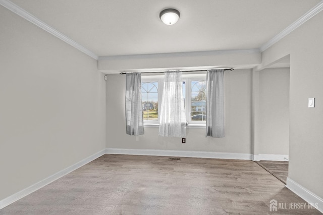 spare room featuring ornamental molding, baseboards, and wood finished floors