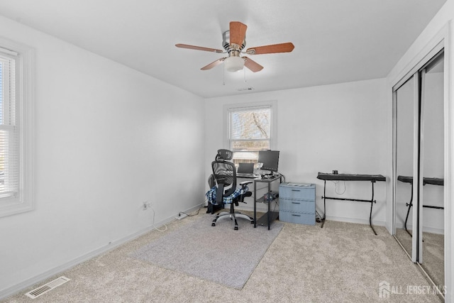 office space featuring carpet floors, visible vents, baseboards, and a ceiling fan