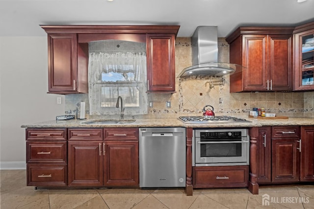 kitchen with stainless steel appliances, a sink, wall chimney range hood, light stone countertops, and tasteful backsplash