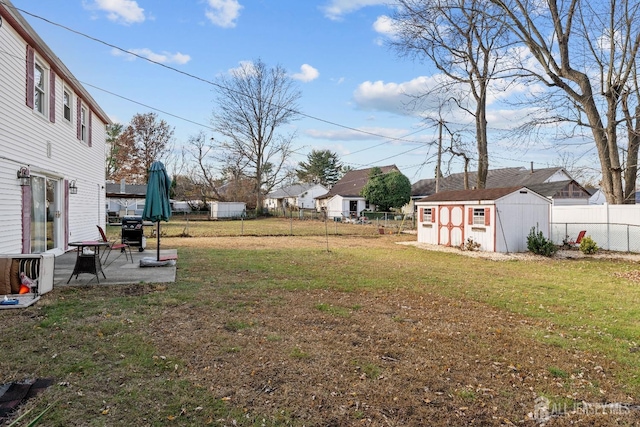 view of yard with an outbuilding, a fenced backyard, a patio, and a shed