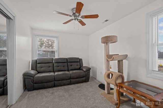 living area with visible vents, plenty of natural light, and carpet flooring