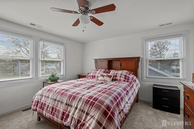 bedroom with light colored carpet, visible vents, and multiple windows