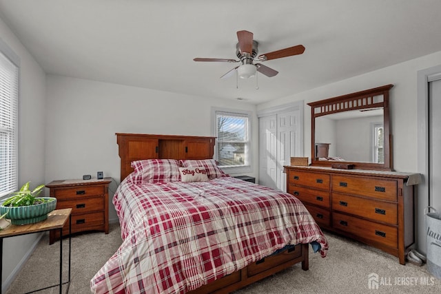 bedroom featuring light carpet, multiple closets, and a ceiling fan