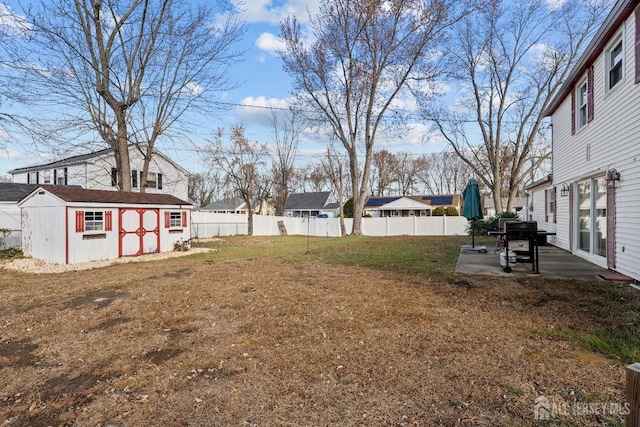 view of yard featuring an outdoor structure, fence, a residential view, a shed, and a patio area