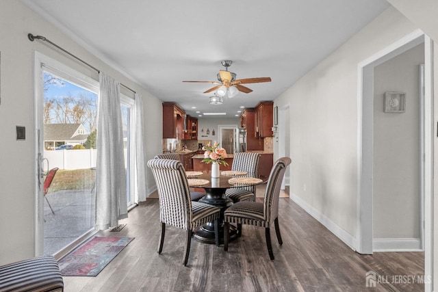 dining space with dark wood finished floors, a ceiling fan, and baseboards