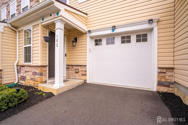 102 Matutina Rd, Monroe, NJ 08831 - view of exterior entry featuring an attached garage, stone siding, and asphalt driveway