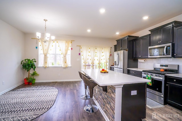 102 Matutina Rd, Monroe, NJ 08831 - kitchen featuring appliances with stainless steel finishes, light countertops, a center island, a breakfast bar, and dark wood-style floors