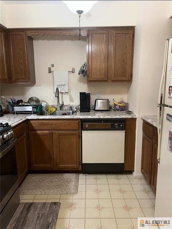 kitchen featuring light stone counters, white appliances, and a sink