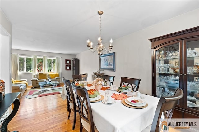 dining space with light wood-type flooring and an inviting chandelier