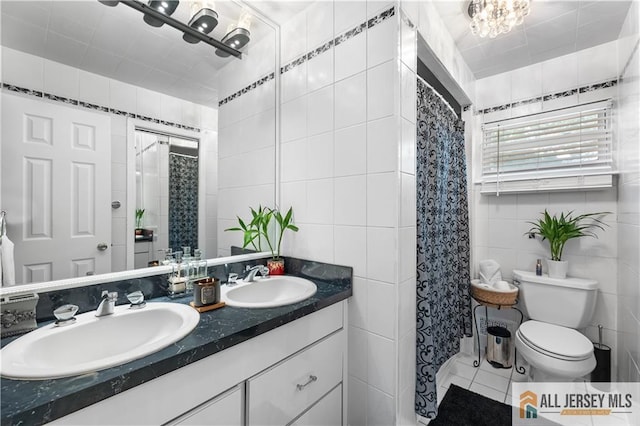 bathroom with tile walls, vanity, walk in shower, tile patterned flooring, and toilet