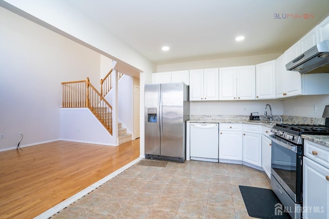 kitchen with appliances with stainless steel finishes, white cabinets, light stone counters, and sink