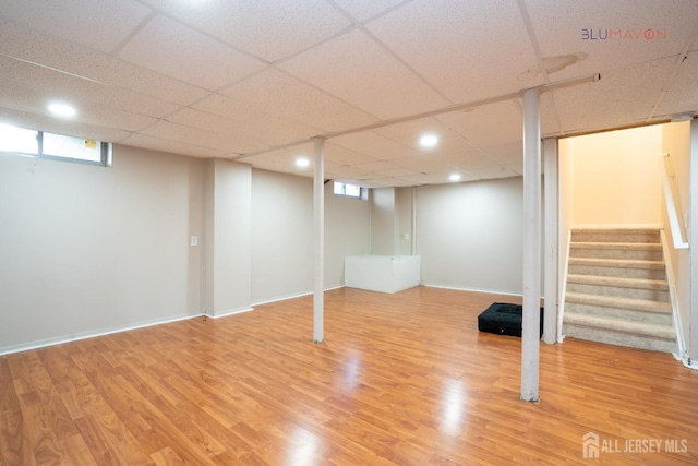 basement with wood-type flooring and a paneled ceiling