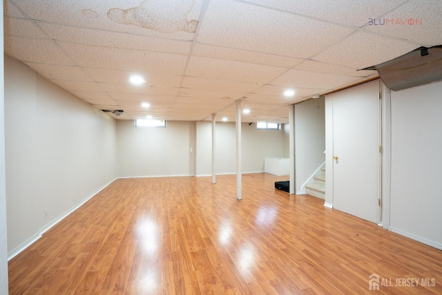 basement with a paneled ceiling and hardwood / wood-style flooring