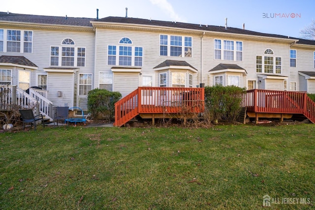 rear view of property with a wooden deck and a lawn