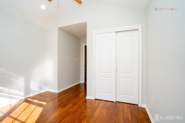 unfurnished bedroom featuring hardwood / wood-style flooring, a closet, ceiling fan, and vaulted ceiling with beams