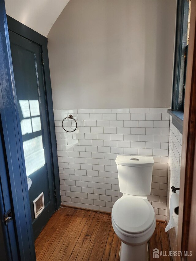 bathroom featuring vaulted ceiling, wood-type flooring, tile walls, and toilet