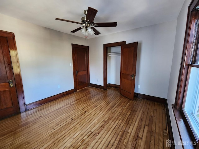 unfurnished bedroom featuring ceiling fan, a closet, and light wood-type flooring