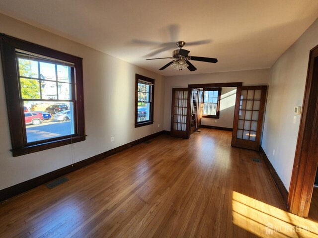 empty room featuring dark hardwood / wood-style floors, ceiling fan, and french doors