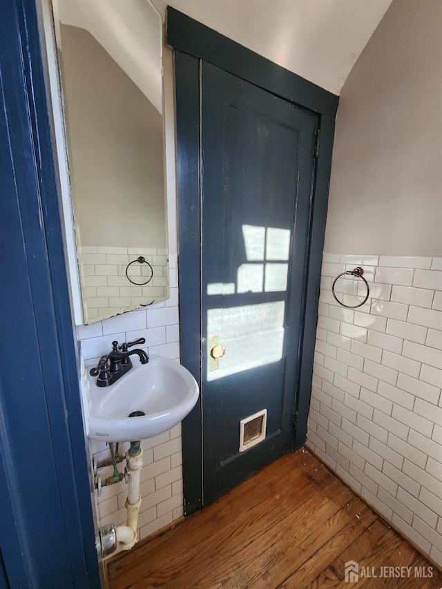 bathroom featuring hardwood / wood-style floors, sink, tile walls, and vaulted ceiling