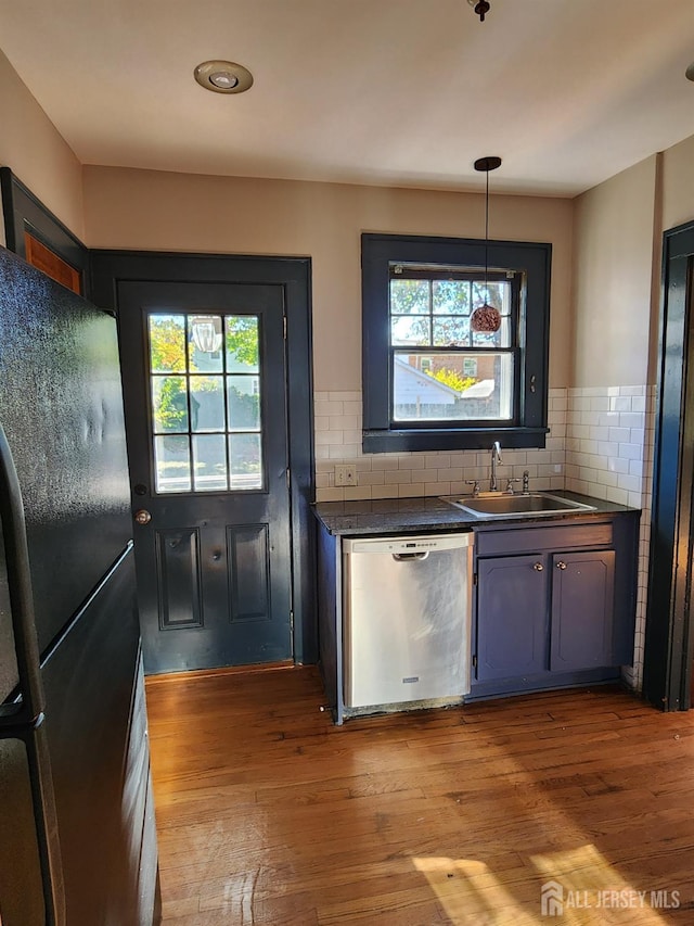 kitchen featuring decorative backsplash, black fridge, sink, light hardwood / wood-style flooring, and dishwasher