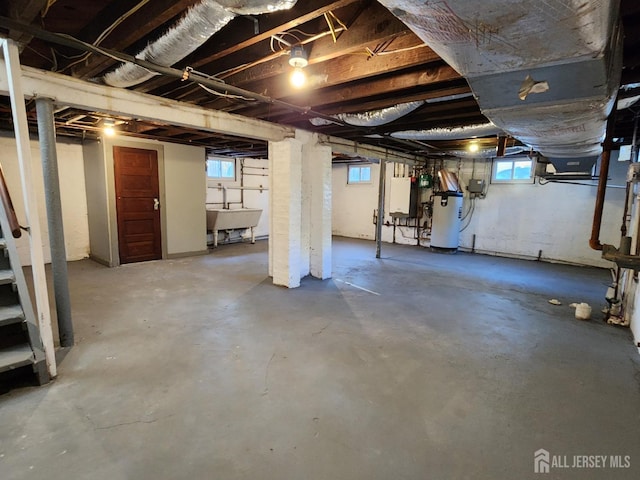 basement featuring water heater, plenty of natural light, and sink