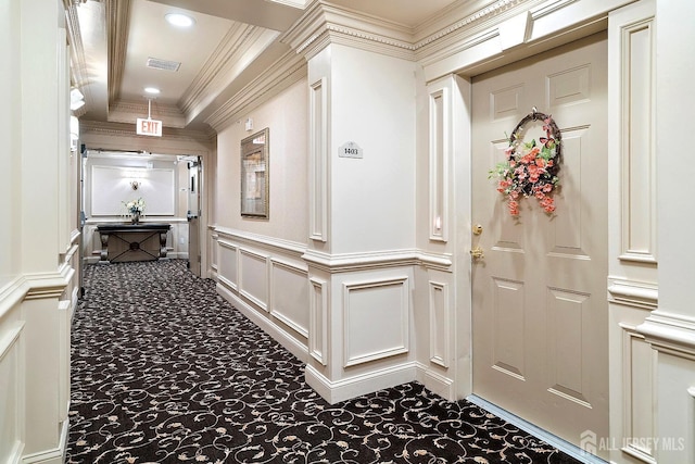 hallway featuring visible vents, ornamental molding, carpet, a decorative wall, and ornate columns