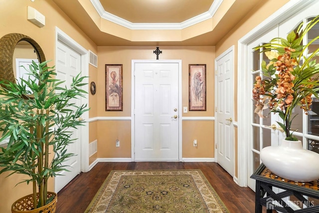 entryway featuring a raised ceiling, crown molding, wood finished floors, and visible vents