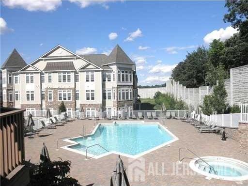 community pool featuring a patio area, a community hot tub, and fence