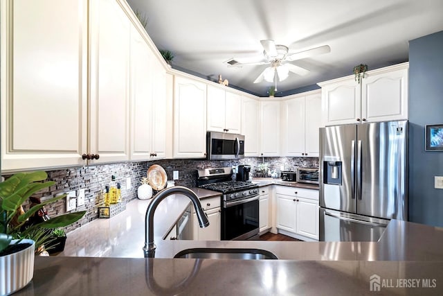 kitchen featuring white cabinetry, dark countertops, backsplash, and appliances with stainless steel finishes