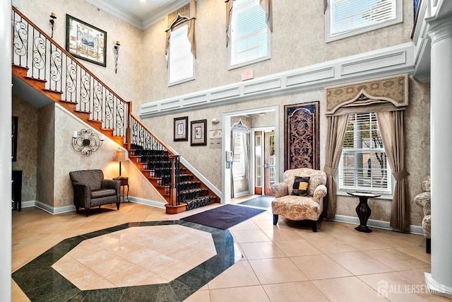 entryway with tile patterned floors, a high ceiling, crown molding, baseboards, and stairs