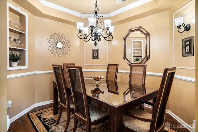 dining room featuring wood finished floors, visible vents, baseboards, a raised ceiling, and a notable chandelier