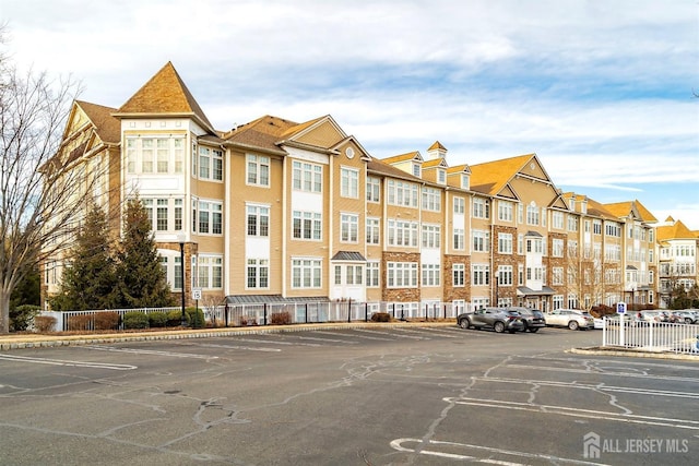 view of building exterior featuring uncovered parking and fence