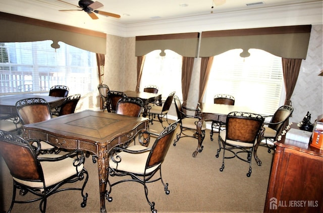 carpeted dining space featuring crown molding, a ceiling fan, and a wealth of natural light