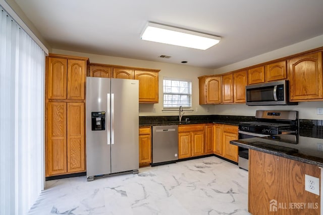 kitchen featuring stainless steel appliances, sink, and dark stone countertops